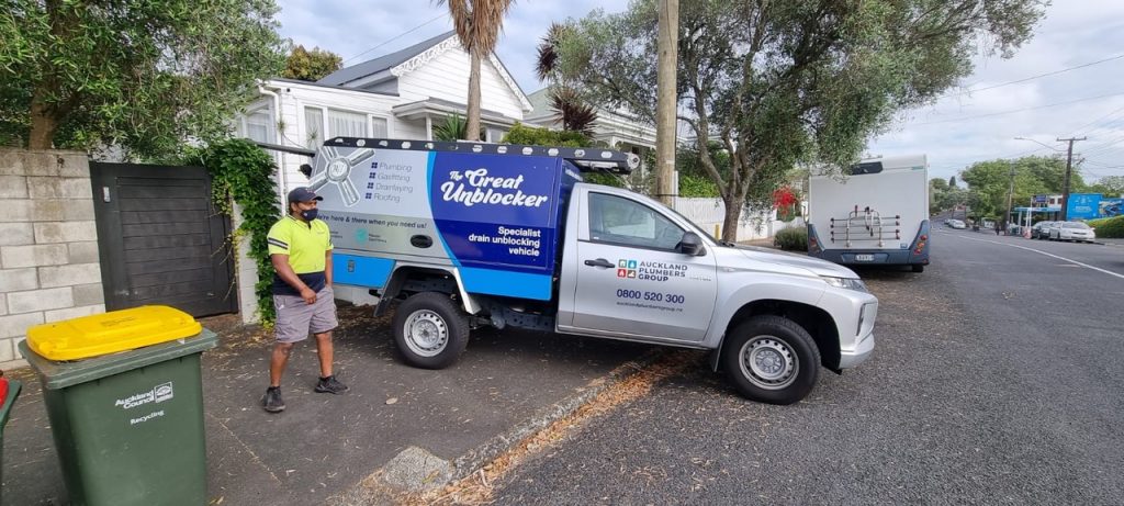“The Great Unblocker” ute parked on side of road with plumber standing nearby