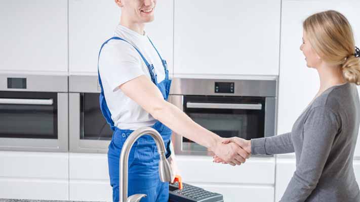 Plumber fixing plumbing issues in rental property, shaking hands with property manager